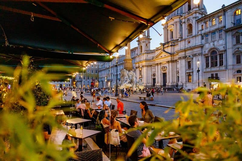 Camillo terrace tables on Piazza Navona at dusk, with Sant'Agnese in Agone in the background
